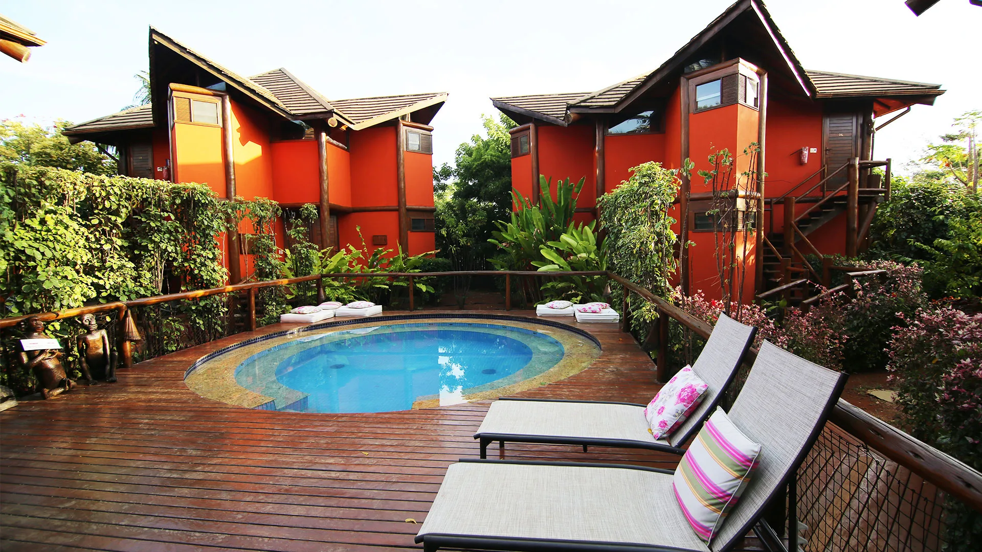 Bangalôs com telhados inclinados ao redor da piscina e do deck de madeira da Pousada Triboju em Fernando de Noronha
