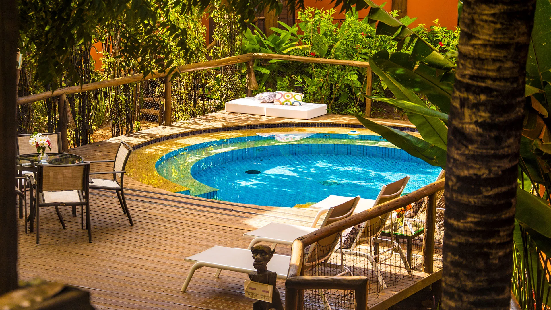 Piscina circular cercada por deck de madeira e bangalôs da Pousada Triboju em Fernando de Noronha