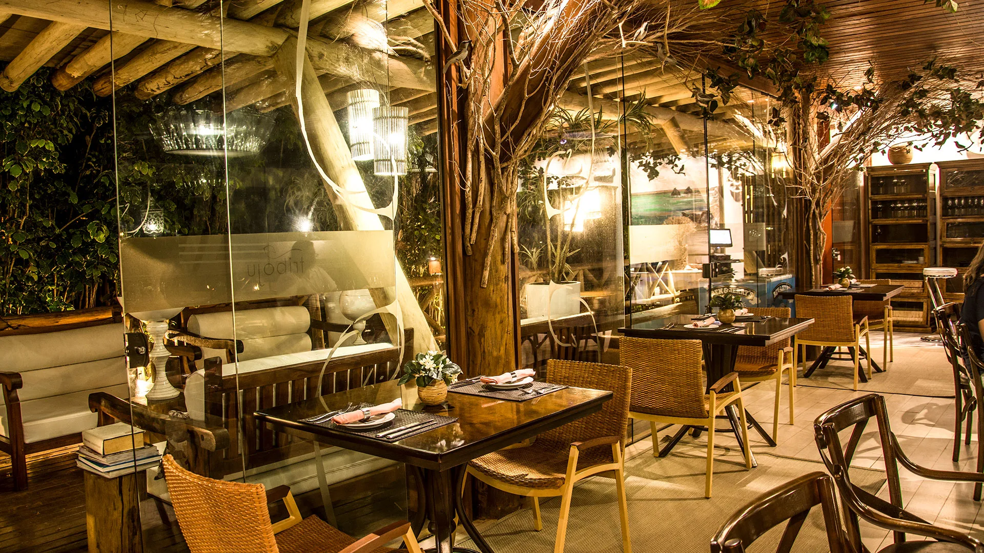 Restaurante iluminado sob cobertura aparente de madeira na Pousada Triboju em Fernando de Noronha