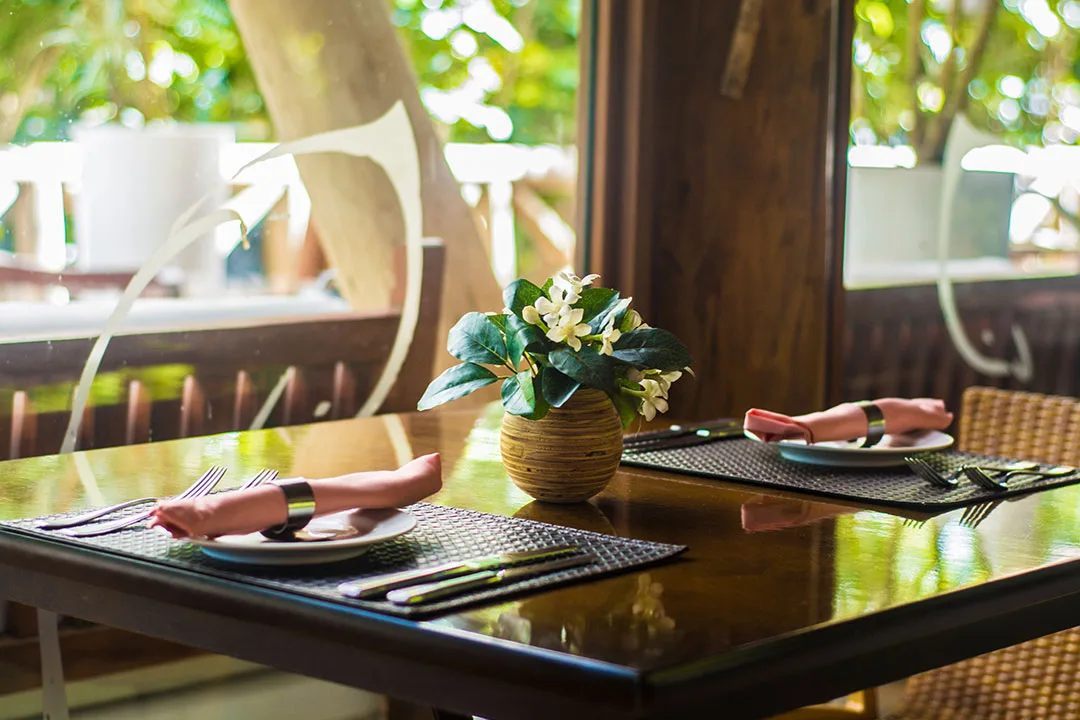 Mesa junto ao deck e aos pilares de madeira do restaurante da Pousada Triboju em Fernando de Noronha